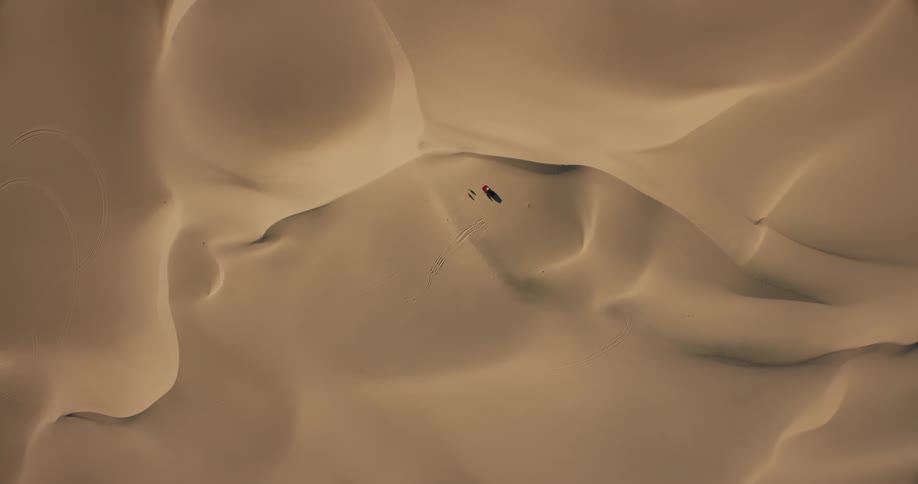 Aerial of a person sitting in the dune desert during a hot day