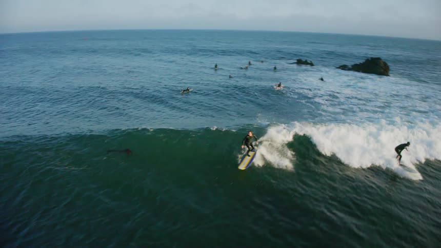 Surfers are riding and waiting for waves ocean under a clear sky near the coast