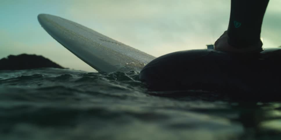 Person sitting on surfboard in the sea on a morning