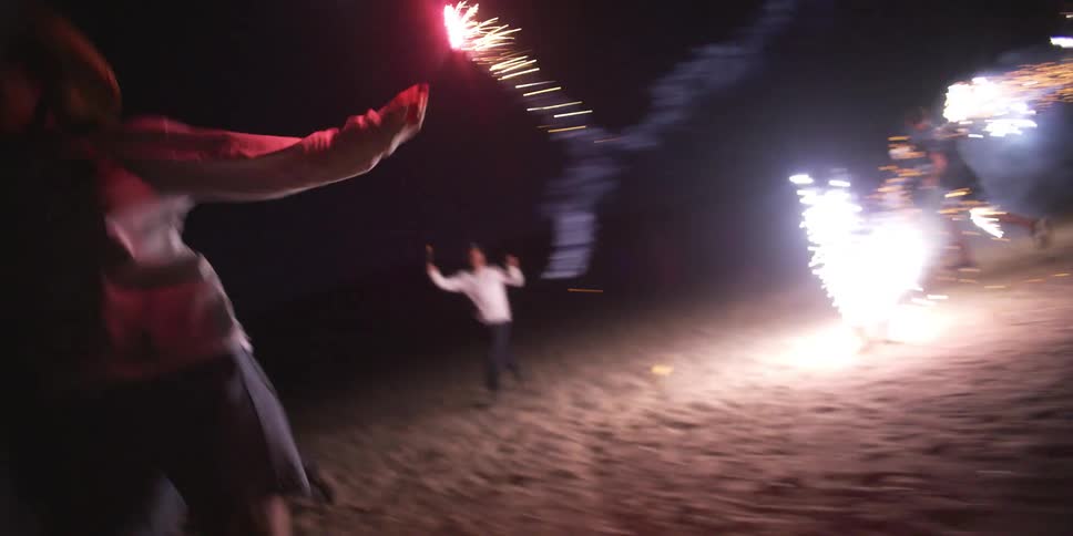 People are running on the beach with fireworks