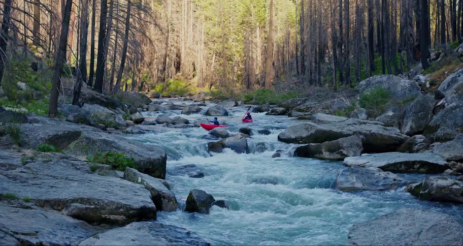 Two people canoeing in the middle of a dangerous river in the forest