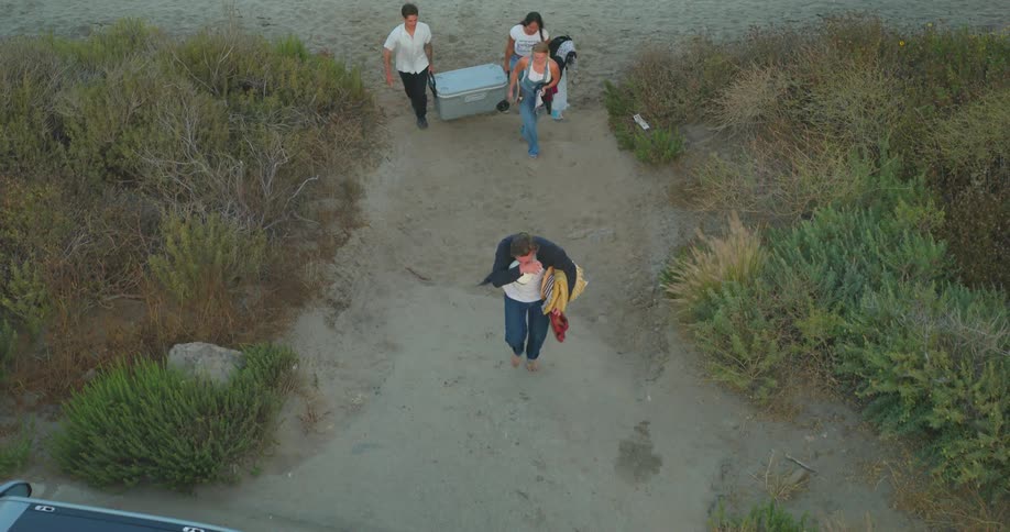 Four people walk across a beach to their vehicle