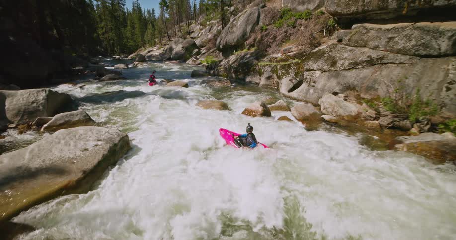 Aerial of people canoeing on a busy river in the forest during the day