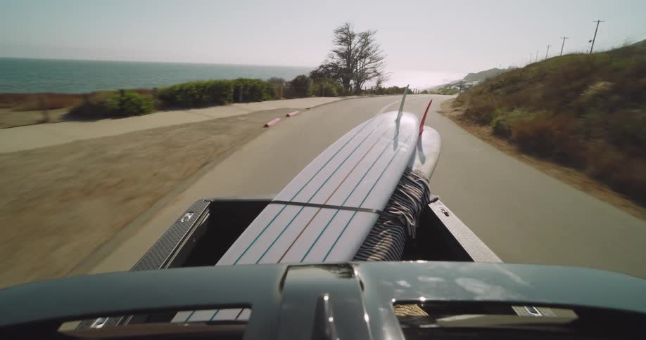 Rear view of a moving pickup truck carrying surfboards