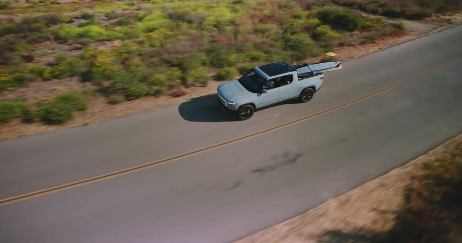 Pickup truck carrying surfboards traveling on a seaside road