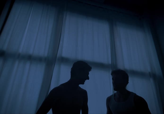 Two men talking in the dark near a window