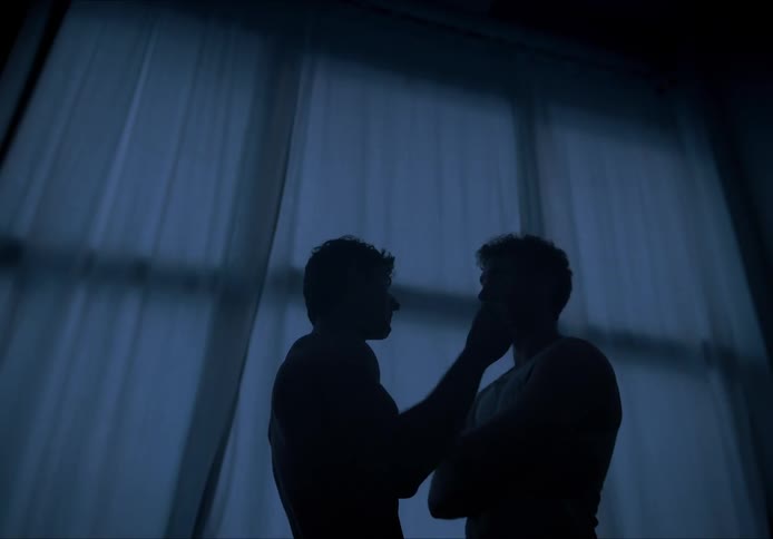 Two silhouettes face each other in a dark room with light coming through the curtains