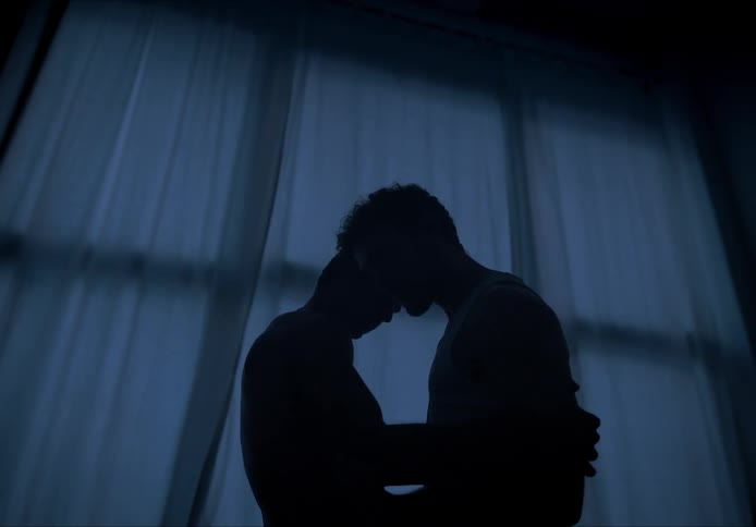 A couple dancing in a dark room at dusk