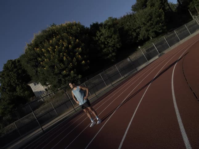 A man standing on an athletics track on a sunny morning