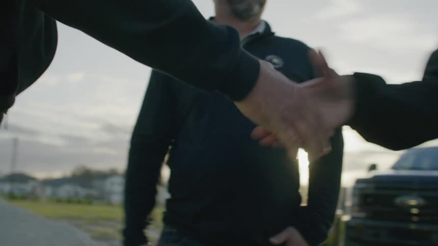 A group of people are shaking hands outdoors at morning