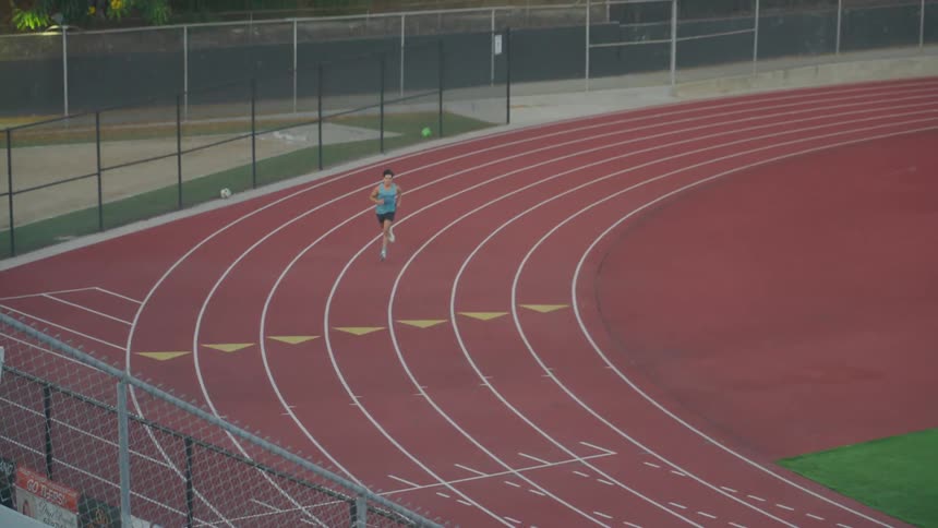 An aerial view of a man running on a running track