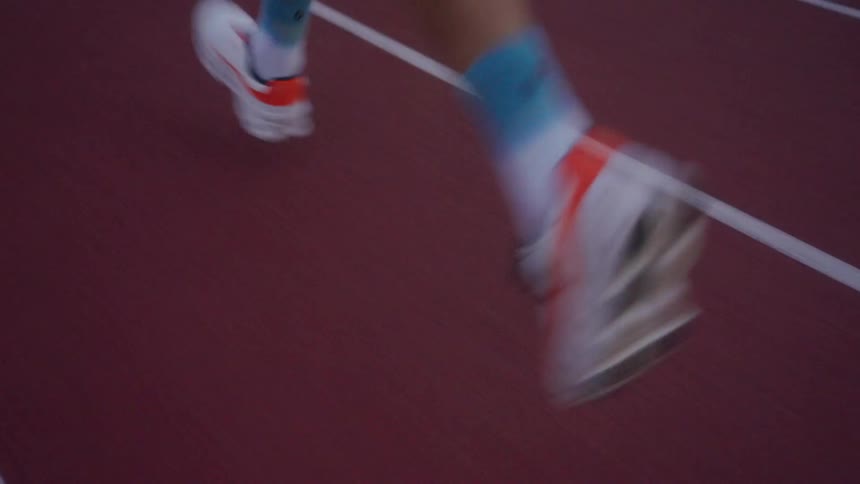 Closeup of a mans legs and sneakers running on an athletics track