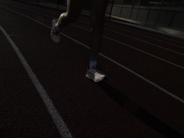 Closeup of a mans legs running on an athletics track in slow motion