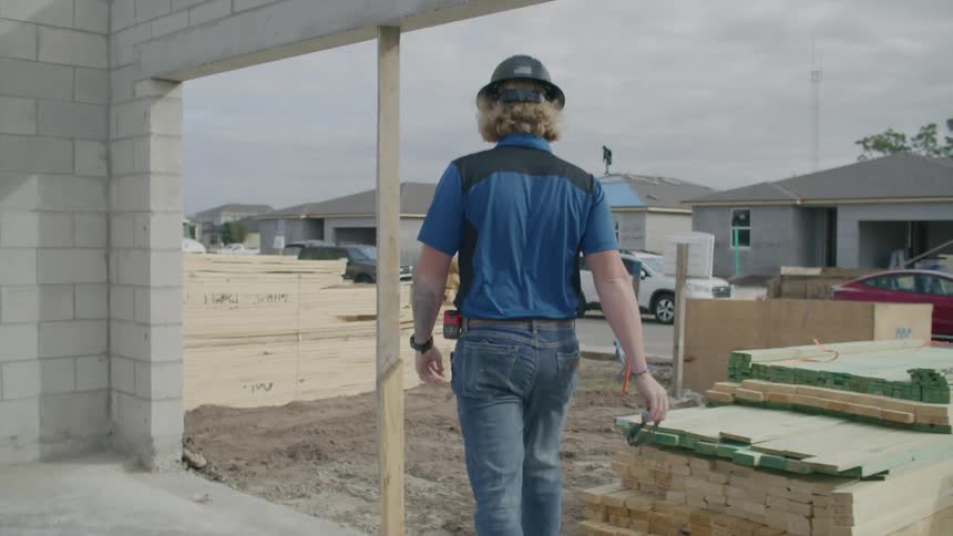 A construction worker walking through a construction site in a suburban neighborhood