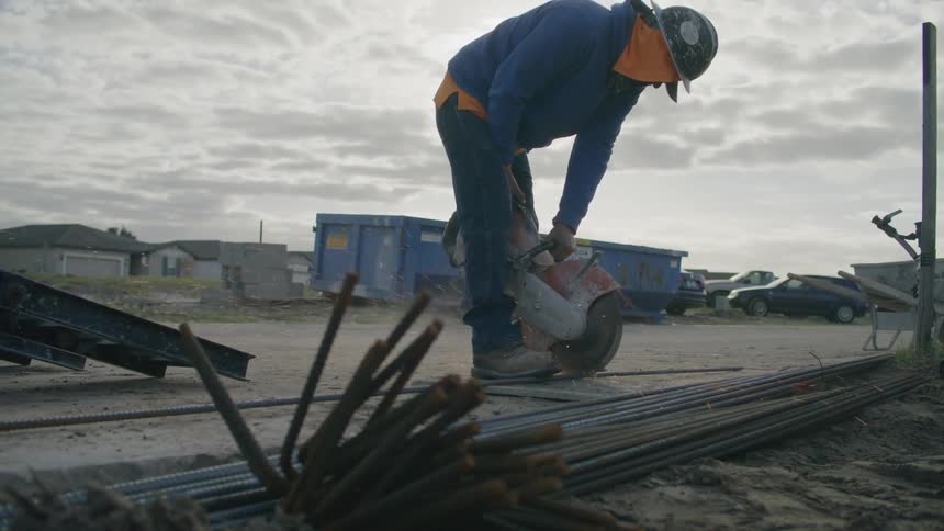 Worker wearing protective helmet with a machine cutting iron