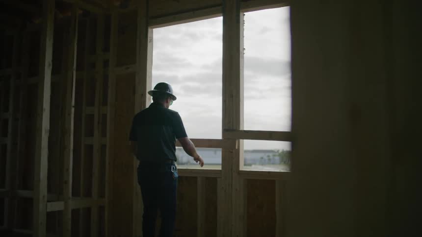 A construction worker looks out of an unfinished window