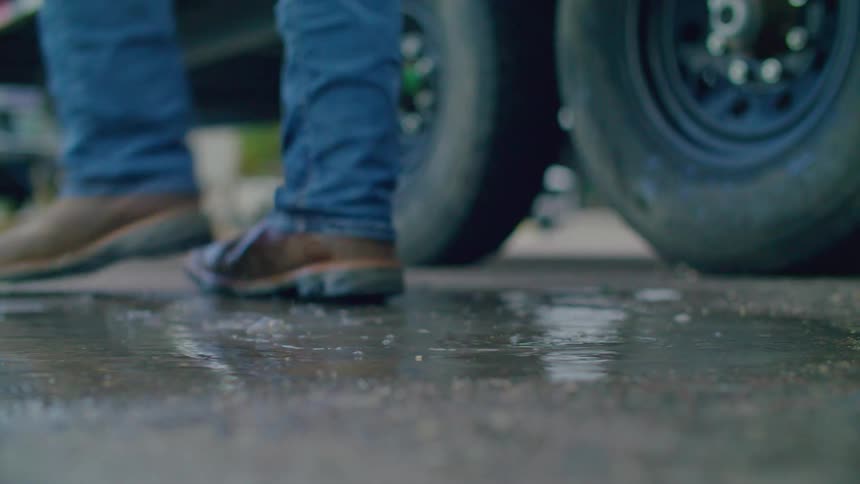 A mans boots cause a water puddle to splash