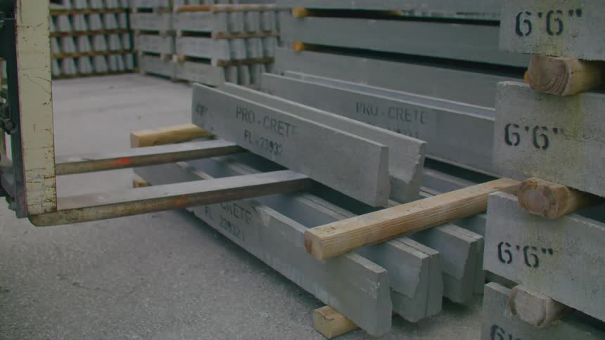 Forklift moves stacked objects separated by wooden beams