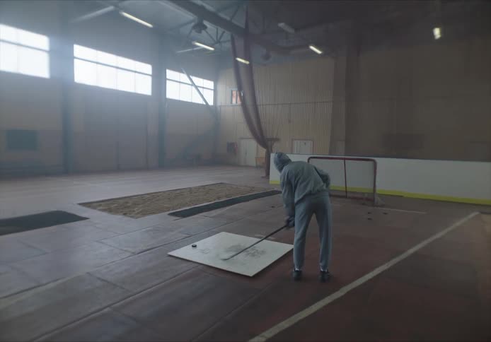 A person practicing hockey on an empty court