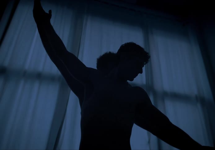 Men dancing in front of a window in a dark room