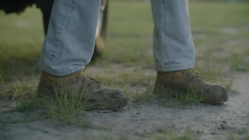 Closeup of a persons worn boots on the grass during the day