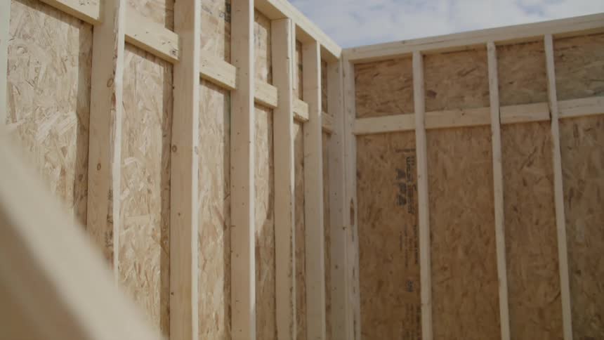 A board moves past a partially framed house