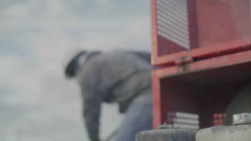 Worker with a shovel putting cement inside a machine