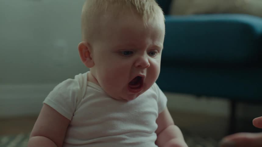 Portrait of a little baby opening its mouth and giving its little hands to its mother