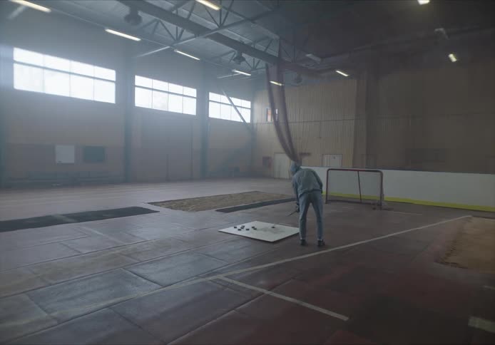 Person training shots on goal in the sport of hockey on a court