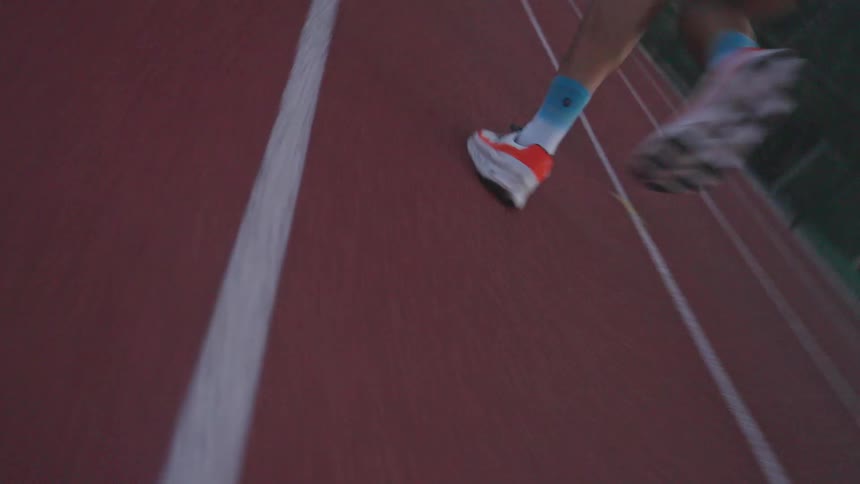 Closeup of an athletes sneakers running on an athletics track during sunset