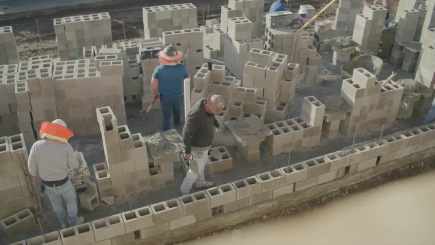 Some workers in a construction site full of cement bricks