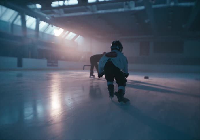 Children practicing hockey on an ice court at dusk