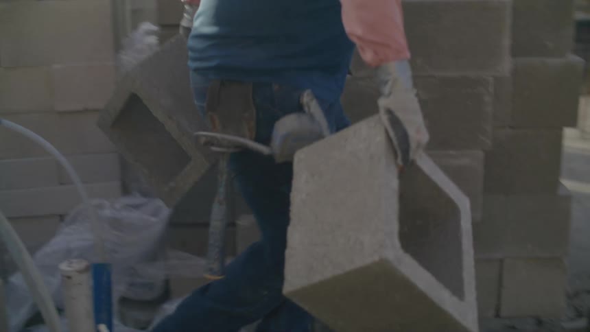 A construction worker is carrying cinder blocks