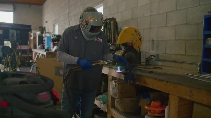 A mechanic using a welding tool in a workshop