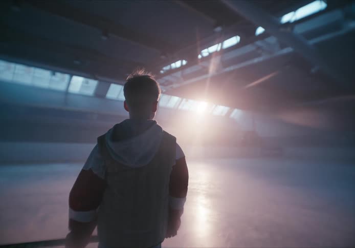 Boy walking around the hockey court with the sun reflecting through the windows
