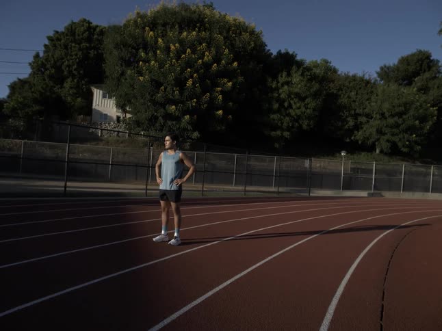 A hispanic teenager stands on a race track