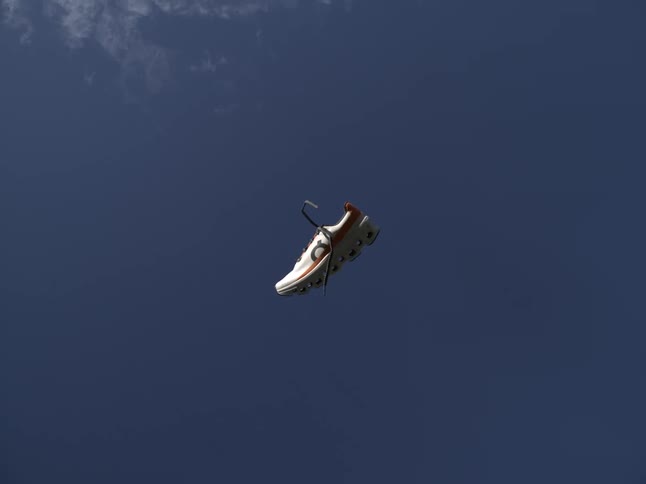 A white sneaker floating in midair against a blue background