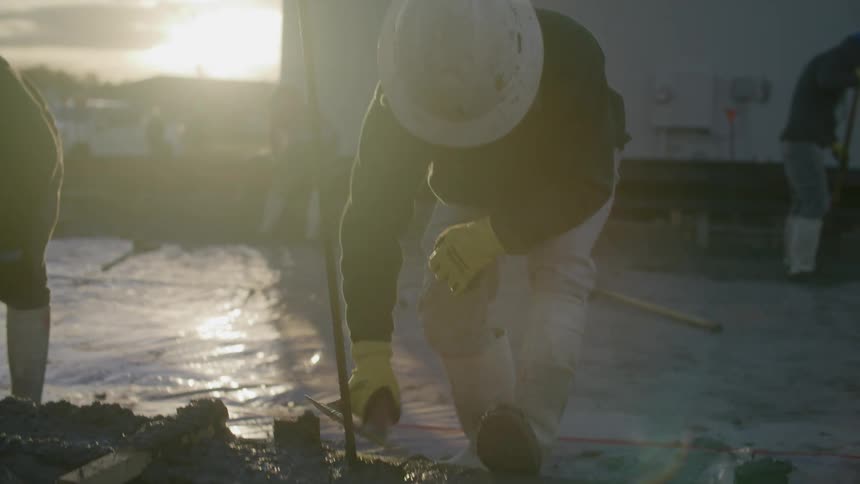 People working at a construction site in a neighborhood during sunset