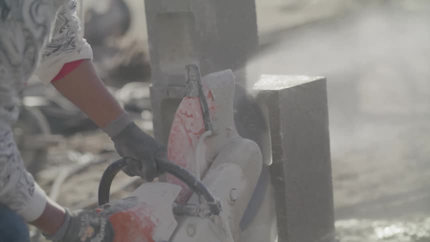 Closeup of a mans hands with a chainsaw cutting a concrete block