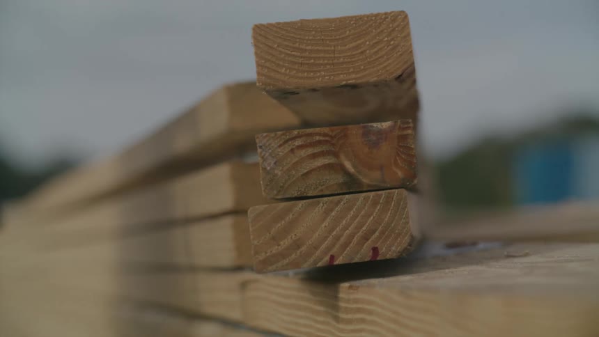 Closeup of a mans hands holding a hammer and pulling apart wooden slats