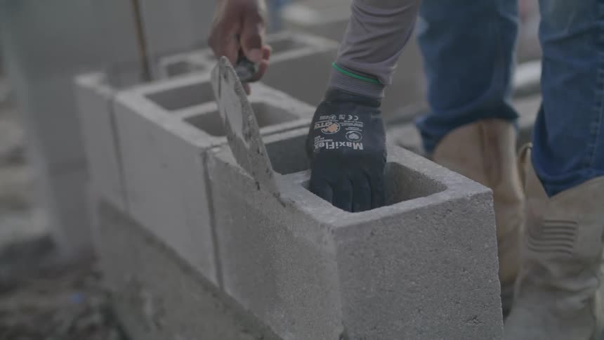 A person aligning bricks with concrete at a construction site