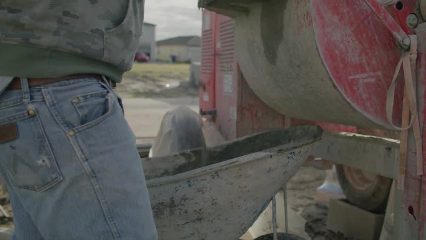 Workers at a construction site placing cement into a cart and being loaded