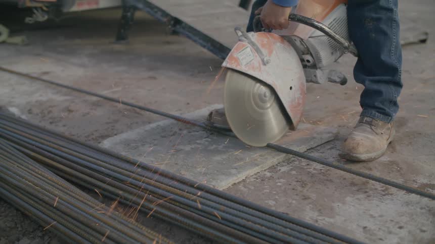 A person cutting iron bars with an electric saw