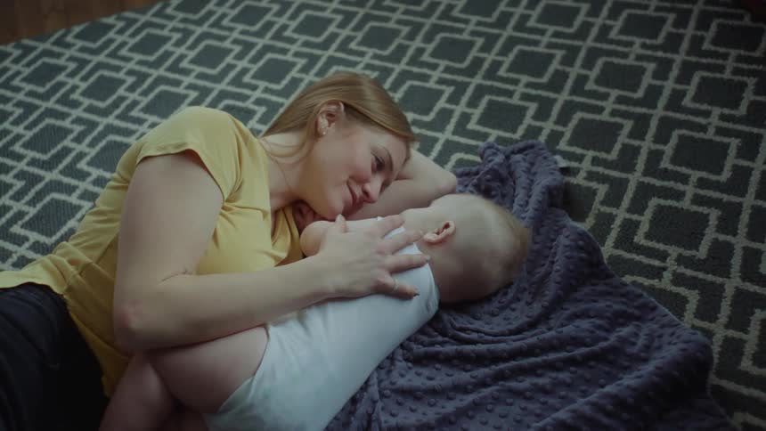 Mother and her infant son resting on a blanket in the living room