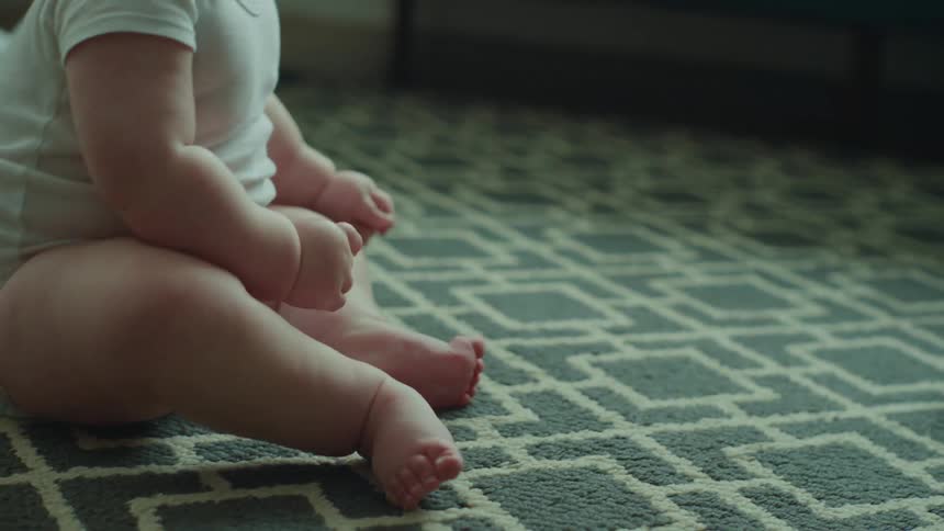 Baby sitting on the living room rug trying to get up