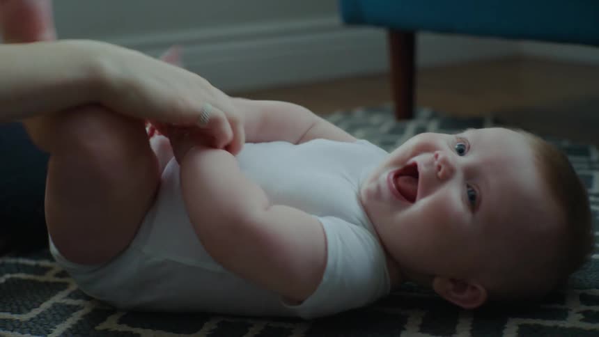Mother tickling a baby on the living room floor