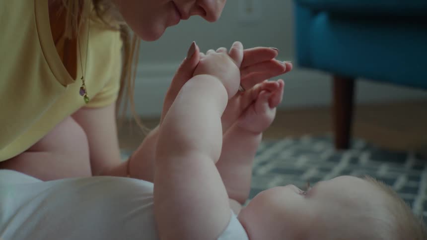A mother lays with her baby on the floor
