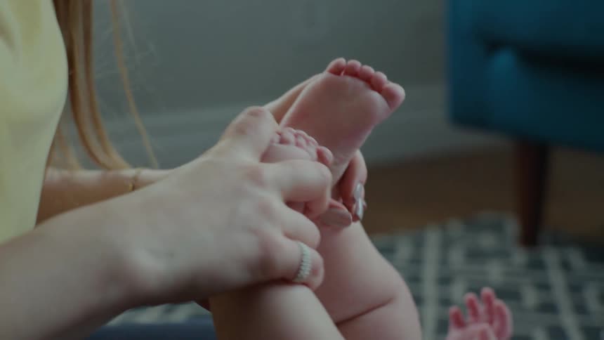 A mother is playing with her baby's feet