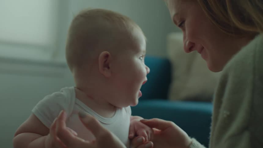 A mother holds her smiling baby while in the room
