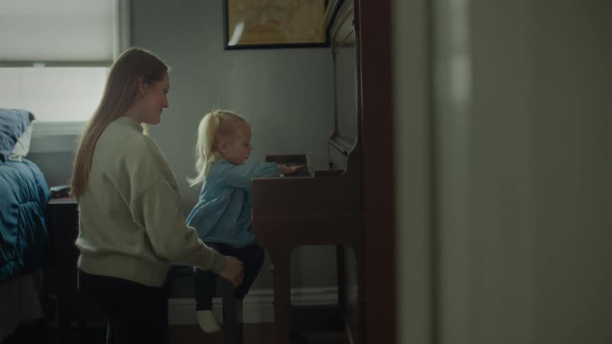 A mother watches her daughter play the piano
